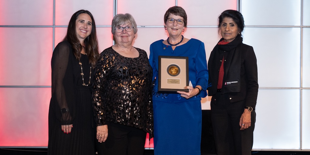 X, X, Danita Forgey holding a plaque for the Maynard Hine Award, IU Indianapolis Chancellor Latha Ramchang (left to right)