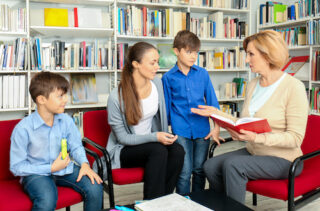 Young mother and children meeting with social worker in library