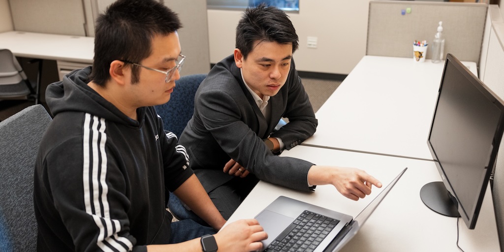 HI student Zhen Hou (left) and HI assistant professor Yan Zhuang looking at laptop computer