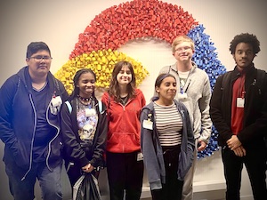 Several iDEW students and faculty chaperone Justin Rice pose in front of Google logo in Chicago office